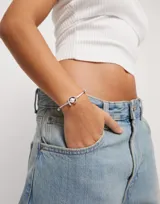 Pulsera de hilo lila con perla shell y fornitura bañada en plata de ley.