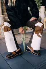 Mocasines de cuero en color dorado con detalles en marrón, con diseño bicolor y costuras artesanales expuestas en el empeine.