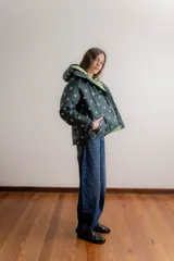 Campera puffer con capucha desmontable, color verde oscuro con estampado de lunares lilas. Cuenta con cierre frontal, bolsillos laterales y forro interno en color verde claro.