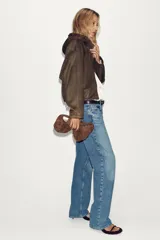 Chaqueta bomber de efecto ante en color marrón, con capucha ajustable mediante cordones, cierre frontal con cremallera, bolsillos laterales y bajo con elástico interior.