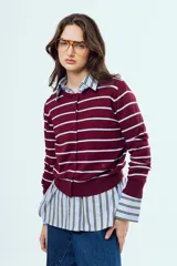 Cardigan de punto color bordó con rayas horizontales celestes, escote redondo y cierre frontal de botones. Cuenta con mangas largas y puños y ruedo elásticos.