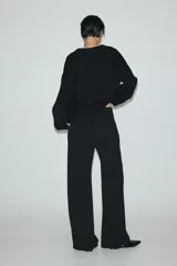 Pantalón ancho de punto color negro, de tiro alto con elástico oculto en la cintura, piernas amplias con pinzas y bolsillos al bies.