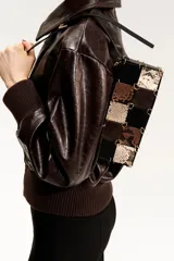 Cartera bandolera rectangular con correa ajustable negra. El cuerpo del bolso está confeccionado con un patrón de patchwork de cuadrados en cuero negro liso, gamuza marrón y estampado de piel de serpiente en tonos beige y marrón. Los paneles están unidos por grapas metálicas doradas. Posee cierre superior y forro interior.
