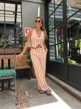 Mono largo a rayas verticales color naranja y blanco, con escote halter y corte ajustado.