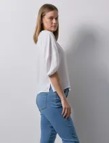 Blusa de gasa blanca con estampado de hojas en azul marino, cuello a la base con escote en V y botones, y mangas cortas abullonadas.