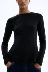 Top de manga larga confeccionado en punto de crepé, con cuello redondo y diseño de peplum. Presenta costuras moldeadoras en la parte frontal y posterior que definen la silueta.