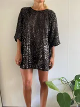 Minivestido negro cubierto de lentejuelas, de corte holgado y manga tres cuartos.