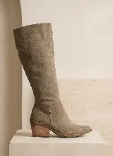 Bota de caña alta confeccionada en cuero vacuno color topo, con taco cuadrado de madera y suela de caucho antideslizante.