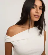 Body blanco de poliéster y elastano, con escote canoa, bretel ancho y detalle torcido en la manga.