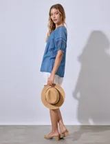 Blusa celeste de lyocell con cuello redondo con lazo, mangas cortas con detalle de puntilla y calado.