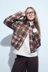 Campera de paño con diseño de cuadros en tonos negro, gris y beige. Presenta cuello camisero, cierre frontal con botones y corte corto.