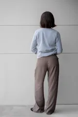 Pantalón de vestir color gris oscuro, de tiro alto y corte palazzo. Presenta una hebilla de metal plateado en el cinturón.