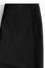 Pantalón sastrero negro de tiro alto, corte ajustado en la parte superior y piernas acampanadas.