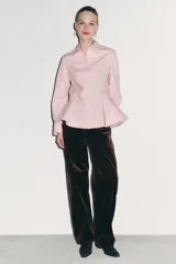 Camisa de popelín de algodón con cuello solapa, manga larga con puños y bajo con diseño peplum. Presenta cierre frontal con botones ocultos por solapa.