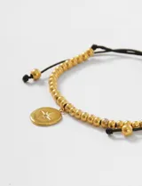 Pulsera ajustable de cordón negro con cuentas metálicas plateadas y un dije circular de acero con diseño de estrella grabada.