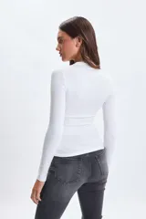 Remera de manga larga con cuello alto, confeccionada en tela lisa de color blanco, con ajuste al cuerpo.