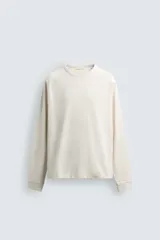 Camiseta de manga larga con cuello redondo, confeccionada en algodón compacto y pesado, con diseño de corte relajado y costuras decorativas en el cuello.