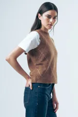 Chaleco de punto gris con diseño de rombos bordados en negro y cuello redondo. Presenta un corte clásico y tejido de textura suave.