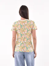 Remera de mangas cortas con cuello redondo y estampado floral en tonos amarillo, naranja, rosa y verde.
