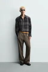 Camisa de corte relajado confeccionada en tejido fluido con mezcla de viscosa. Presenta diseño de cuadros en tonos grises y azul oscuro, cuello solapa, manga larga con puños abotonados y cierre frontal de botones.