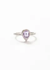 Anillo de plata 925 con una zirconia central en forma de gota color violeta, rodeada de pequeñas zirconias transparentes.