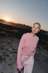 Sweater de punto color rosado con cuello redondo y manga larga, de bajo asimétrico con acabados en rib.