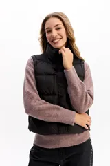 Chaleco matelaseado de color negro, con cuello alto, cierre frontal con broches y diseño acolchado con volumen.