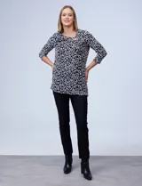 Blusa azul con estampado de círculos negros, de tejido texturado con escote en V descentrado y aplique de aro metálico.