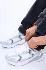 Championes urbanos de diseño clásico, confeccionados en una combinación de cuero sintético y tejido de malla. Presentan una base blanca con detalles en gris y acentos en azul oscuro, con suela de goma robusta y cierre de cordones.