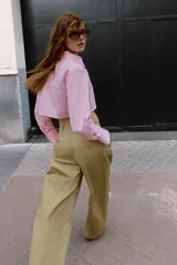 Camisa corta rosa con rayas verticales finas, cuello solapa, manga larga y bolsillos delanteros de plastrón. Cierre frontal con botones ocultos.