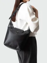 Cartera de hombro Longchamp modelo Le Pliage Xtra, confeccionada en cuero negro con diseño minimalista, solapa frontal con cierre de botón a presión y correa ajustable.