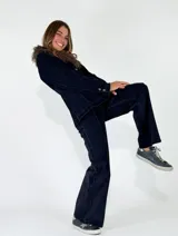 Chaqueta de denim azul oscuro con cuello de piel sintética desmontable, cierre frontal con botones metálicos y bolsillos delanteros con solapa.