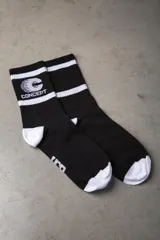 Medias de caña media color negro con detalles en blanco. Presentan dos franjas horizontales blancas en la parte superior, el logo de la marca Concept en el lateral y puntera y talón en color blanco.