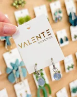 Aros de argolla pequeña de acero con dije colgante de piedra esférica en color celeste.