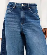 Pantalón barrel en jean de tiro alto con calce amplio y botamanga levemente afinada, de color azul, con recortes laterales, pespuntes contrastantes y bolsillos funcionales.