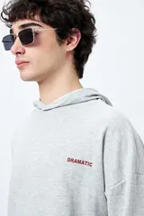 Canguro marrón con capucha, bolsillo frontal y puños ajustados. Estampa frontal con la palabra 'Dramatic' y gráfico en la espalda con tipografía bold y serpiente ilustrada.