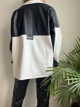 Campera con capucha, de cuero sintético, con diseño color block en blanco y negro y cierre frontal.