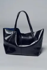 Bolso formato maxi shopper de piel con acabado brillante, detalle de pespuntes a tono y asas de hombro. Incluye una cartera extraíble con cierre y logo de la marca grabado.