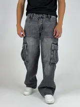 Pantalón de jean gris oscuro lavado, estilo cargo y corte baggy, con múltiples bolsillos laterales y calce holgado.