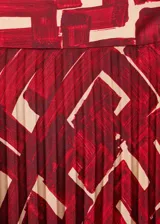 Falda midi plisada de tejido satinado con diseño evasé y estampado geométrico en tonos rojos y beige. Cuenta con cierre de cremallera invisible en el lateral.