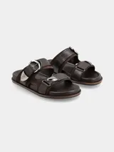 Sandalias planas de cuero marrón, con dos tiras anchas en el empeine provistas de hebillas metálicas plateadas de estilo western.