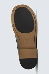Zapato náutico de piel color negro con diseño liso, detalle de bordón en el empeine, horma cuadrada y suela con ligero tacón.