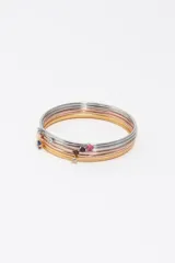 Set de pulseras rígidas de metal en tonos plateado, dorado y rosé, cada una con un pequeño cristal de color incrustado.