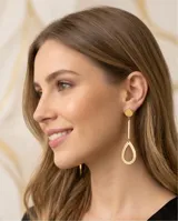 Caravanas colgantes de acero con baño de oro, compuestas por un disco superior y un dije inferior en forma de gota alargada.