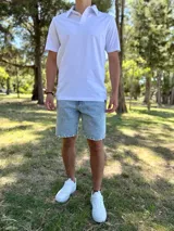Remera chomba blanca de manga corta, con cuello polo y cierre frontal de botones ocultos.