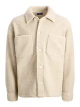 Sobrecamisa de textura teddy, color beige, con cuello camisero, cierre frontal de botones, mangas largas con puños abotonados y dos bolsillos frontales en el pecho.