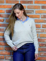 Buzo de lana color beige con escote en V y cuello tipo polo. Presenta un diseño de tejido de punto con puños y ruedo acanalados, y un pequeño bordado decorativo en el pecho.