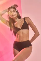 Conjunto de bikini negro confeccionado en lycra brillante. El corpiño es de estilo triángulo con breteles anchos fijos y pinzas para dar volumen. La bombacha es de tiro medio.