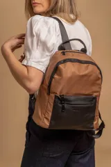 Mochila urbana de diseño combinado, confeccionada en tela resistente con bolsillo frontal y detalles en cuero sintético. Cuenta con compartimento principal con cierre y correas ajustables.