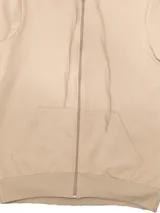 Campera deportiva unisex color beige, confeccionada en algodón con felpa, con capucha, cierre frontal y bolsillo tipo canguro.